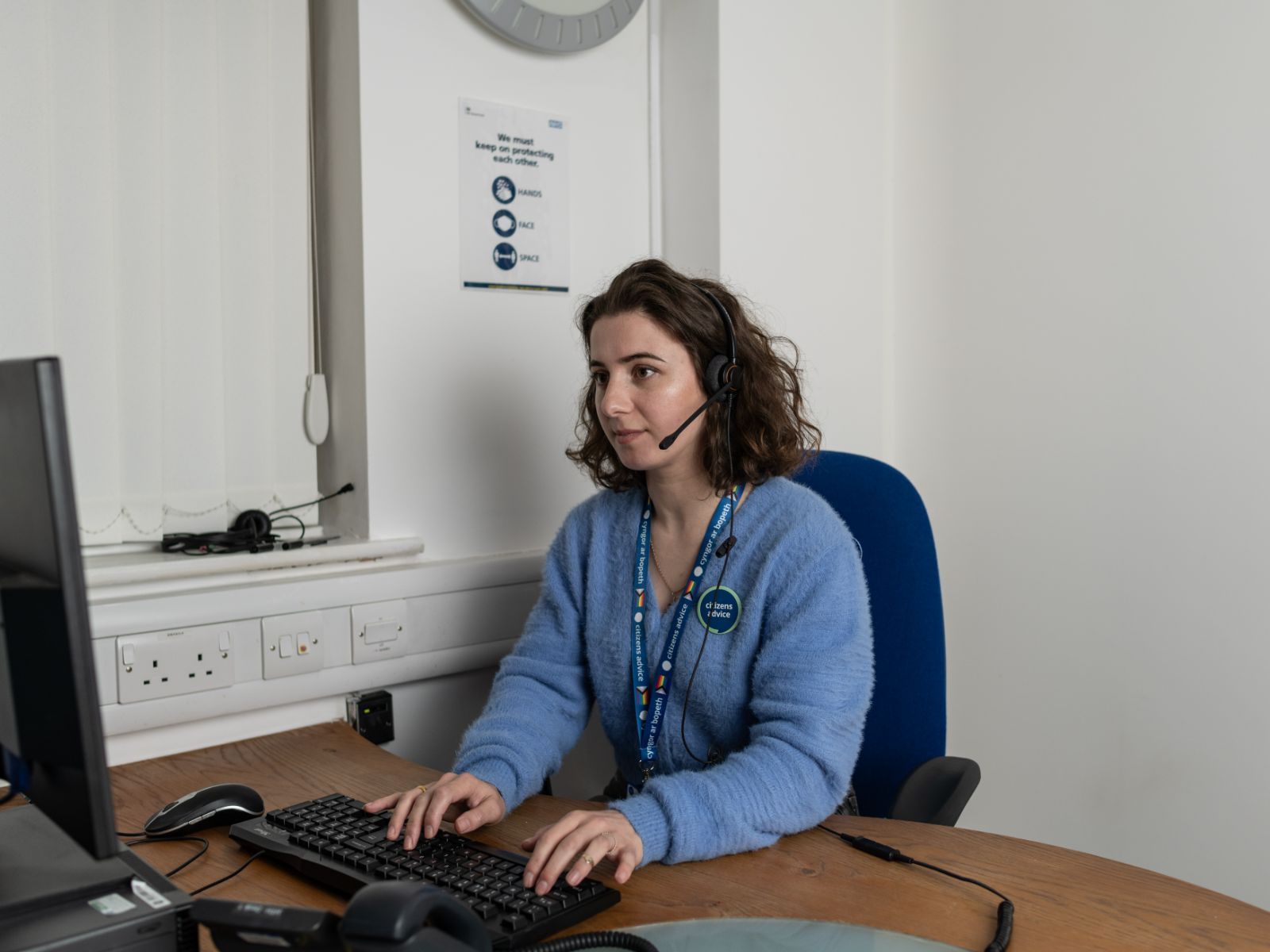 Neutral-adult-at-work-at-CA-with-bilingual-lanyard Advicelink Cymru Advice Services